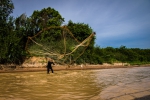 Fisherman throwing fishnet high into the air