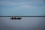 Two fishermen fixing fishnet on a boat