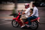 Family of three on a red Suzuki scooter