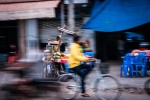 Yellow hoodie cycling past food stall