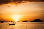 Sun setting down behind children on a boat