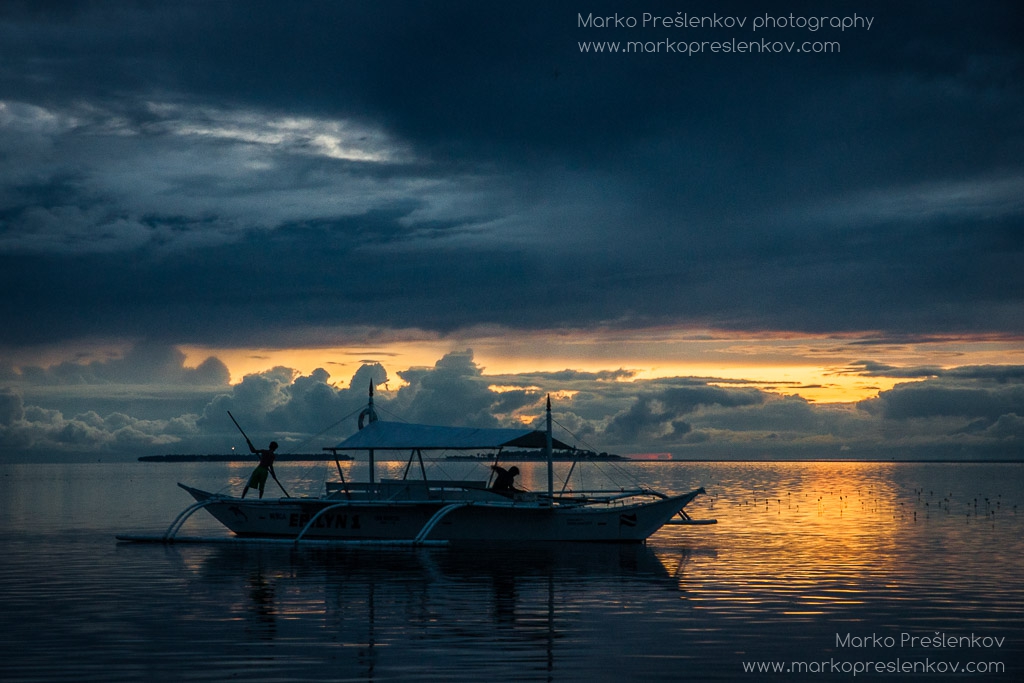 Boy pushing a bangka boat with a long pole in sunset