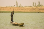 Boy using a pole to push pinasse across the river