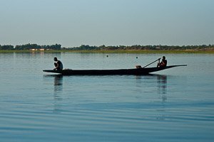 A man and a kid working in the late afternoon on their pirogue on the Niger river near ferry crossing to Timbuktu, Mali. Photo by Marko Preslenkov.