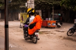 Buddhist monk sitting sideways on a speeding scooter