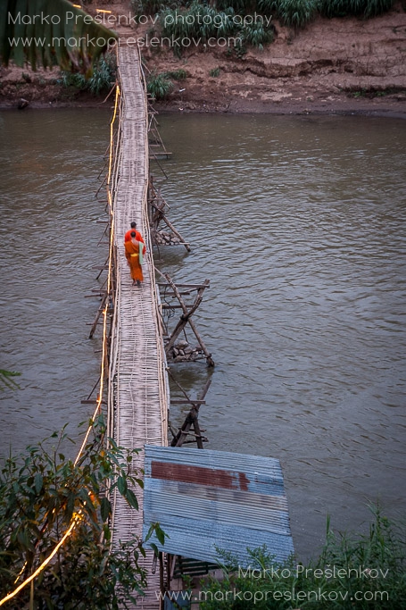 Buddhist monks strolling over bamboo bridge